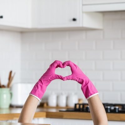Heart made of pink protective gloves on white kitchen background.. Woman hands wearing protective gloves. Concept of clean kitchen, successful thumb up yes ok sign
